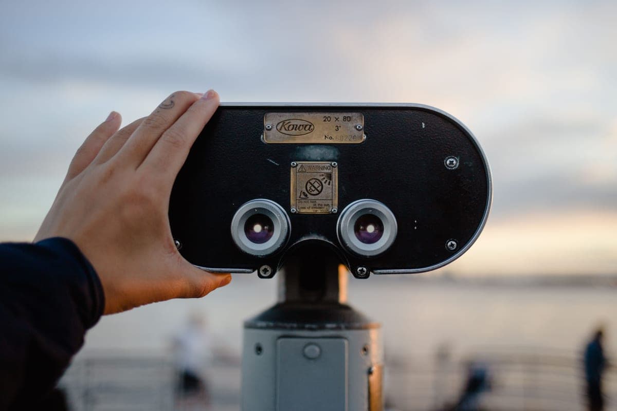 Hands holding binoculars up toward a dark night sky