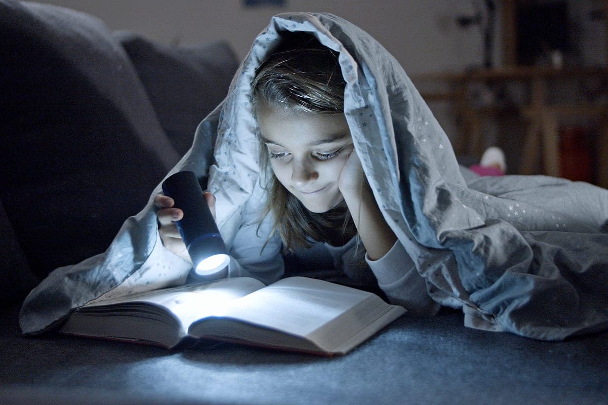 A child reading by torchlight at night