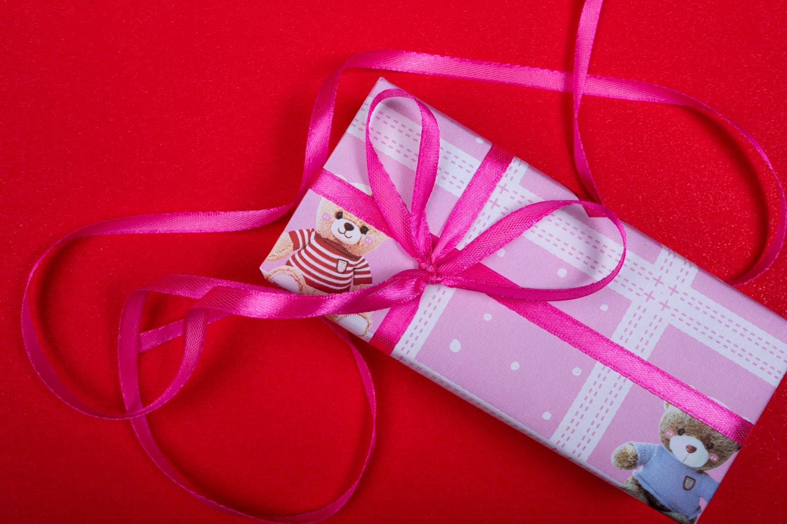 A wrapped gift box tied with ribbon on a plain surface