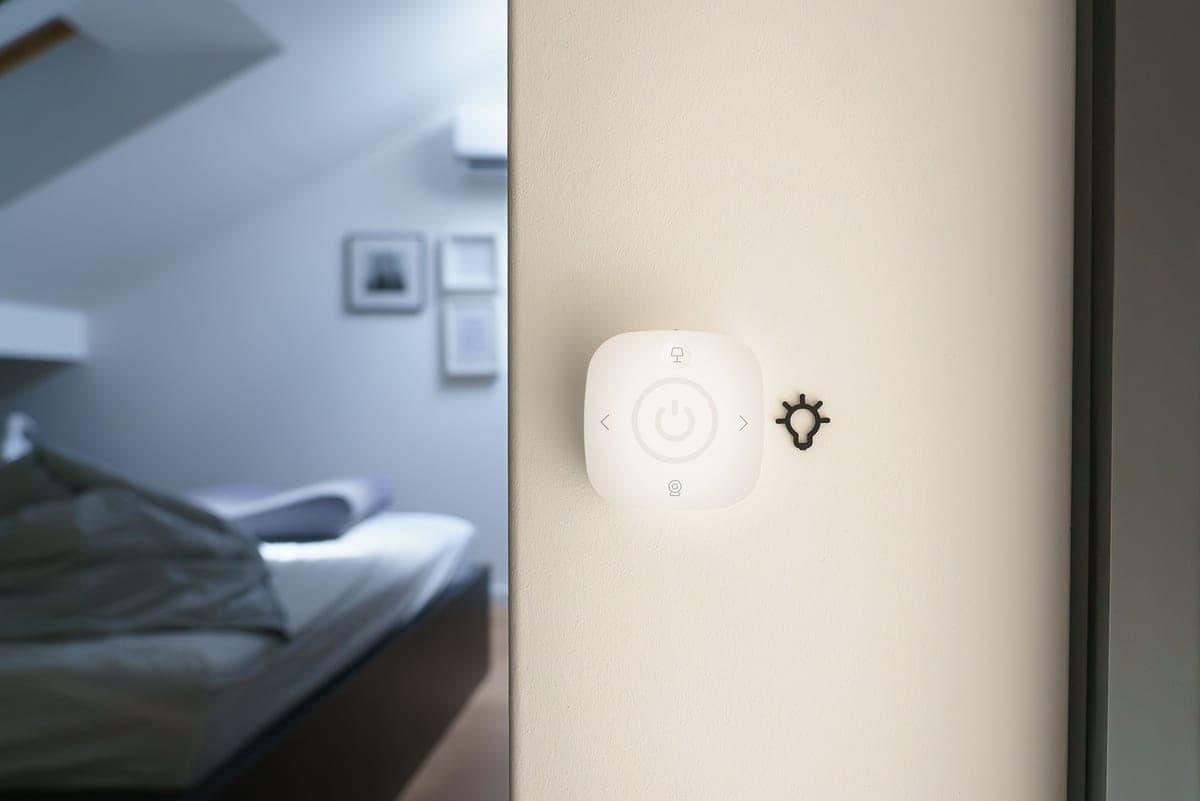 A phone showing a smart home app beside a bedside table
