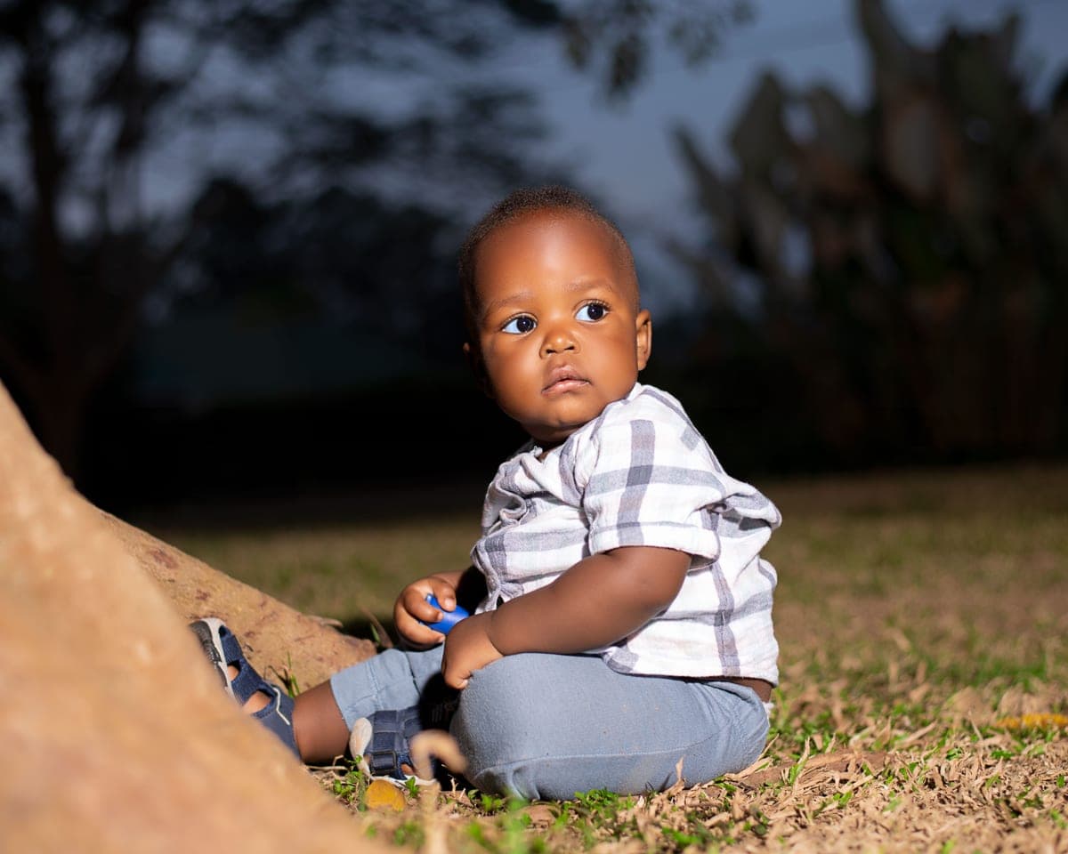 A young child outdoors in the early evening, looking upward